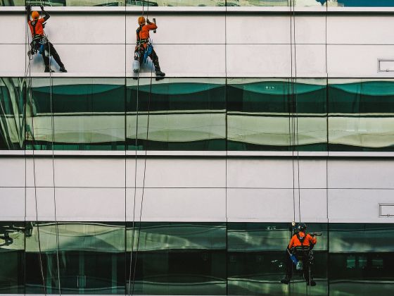 Drei Höhenarbeiter bei der Reinigung einer Gebäudefassade am Seil