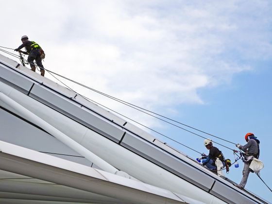 Arbeiter mit persönlicher Schutzausrüstung auf Dach