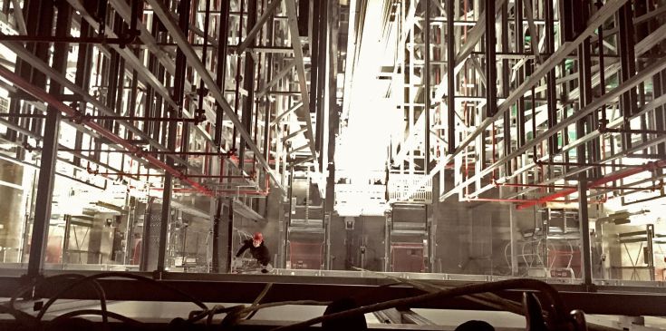 Höhenarbeiter bei Elektroinstallation in Produktionshalle, fotografiert von oben