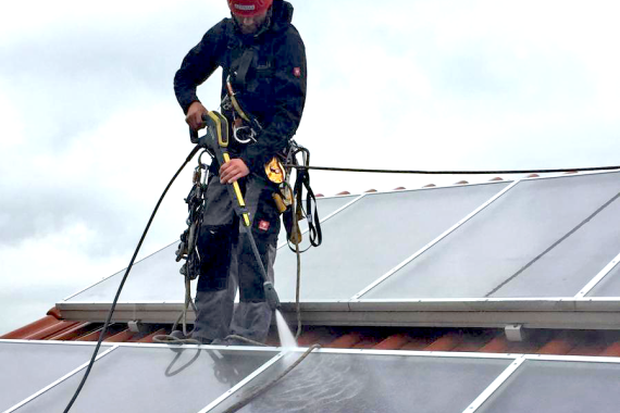 Höhenarbeiter bei der Reinigung von Solarzellen auf Dach
