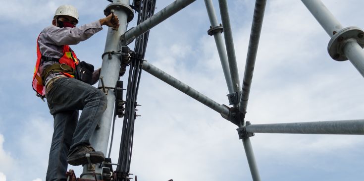 Elektroinstallation mit Industriekletterer an Mast in großer Höhe