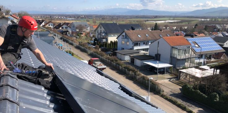 Höhenarbeiter auf Dach bei der Montage von Taubenspikes an einer Solaranlage