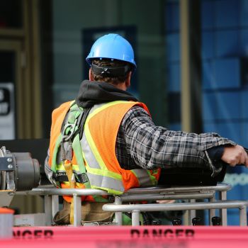 Bauarbeiter von hinten auf Hebebühne gesichert mit PSA gegen Absturz