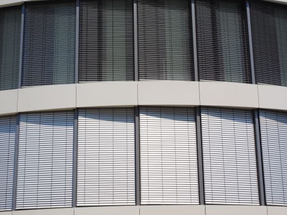 Geschlossene Jalousien zum Sonnenschutz über alle Stockwerke an Fassade von hohem Gebäude